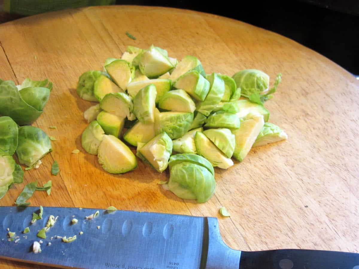 Chopped Brussels sprouts on a wooden cutting board.