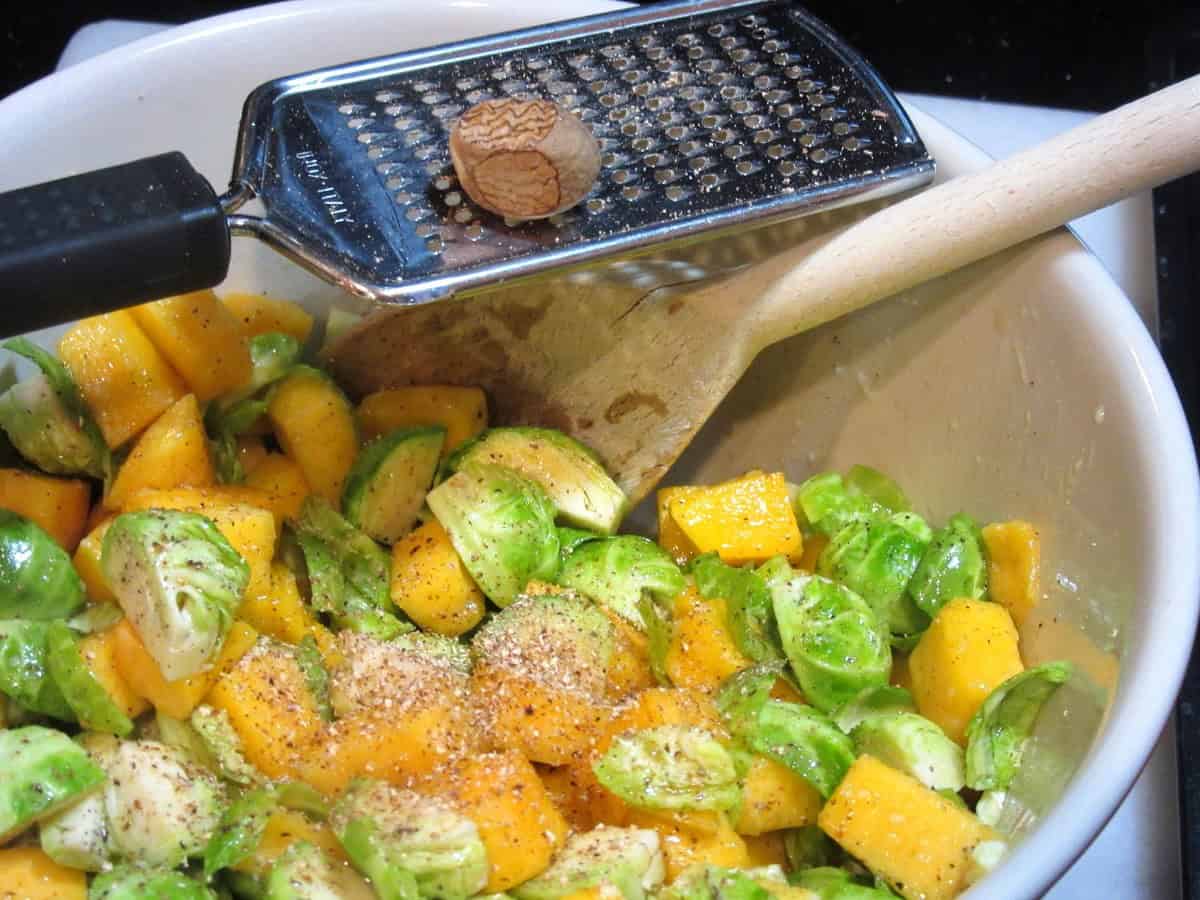 Freshly grated nutmeg in a bowl with Brussels sprouts and butternut squash.