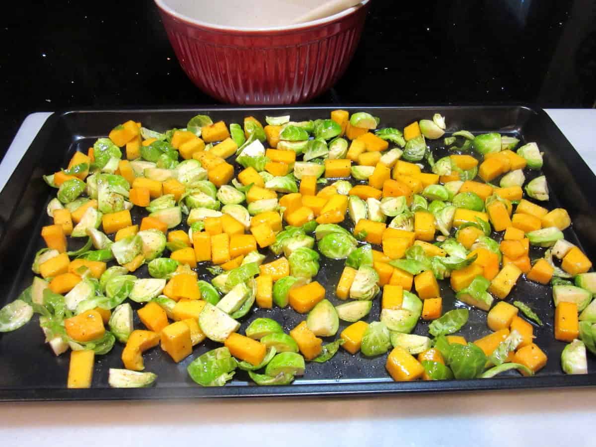 Chopped Brussels sprouts and butternut squash on a baking sheet before roasting.