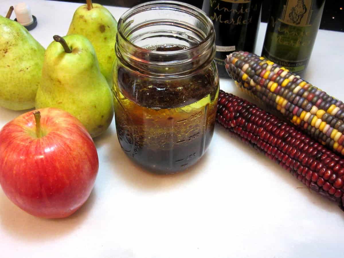 Pumpkin vinaigrette in the making with pears and apples next to the jar.
