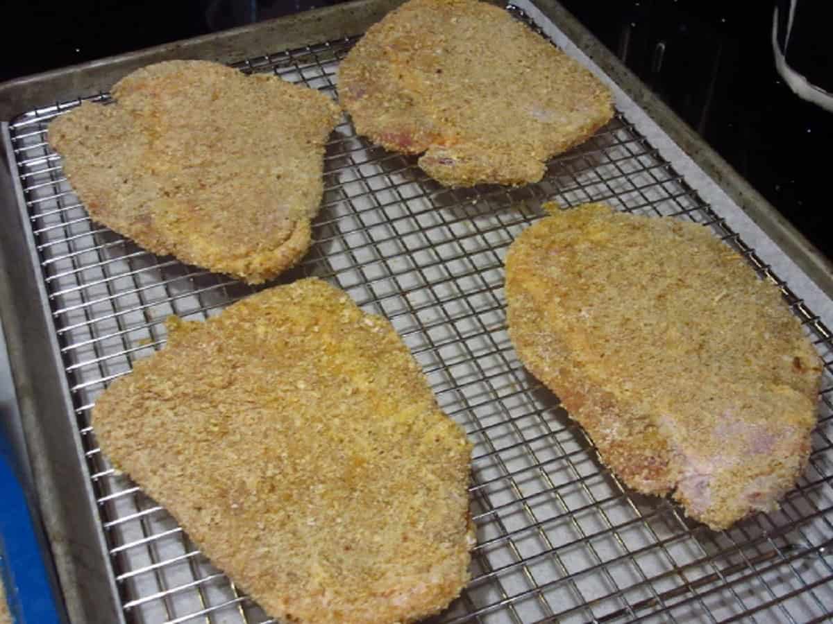 Four breaded pork cutlets before browning.