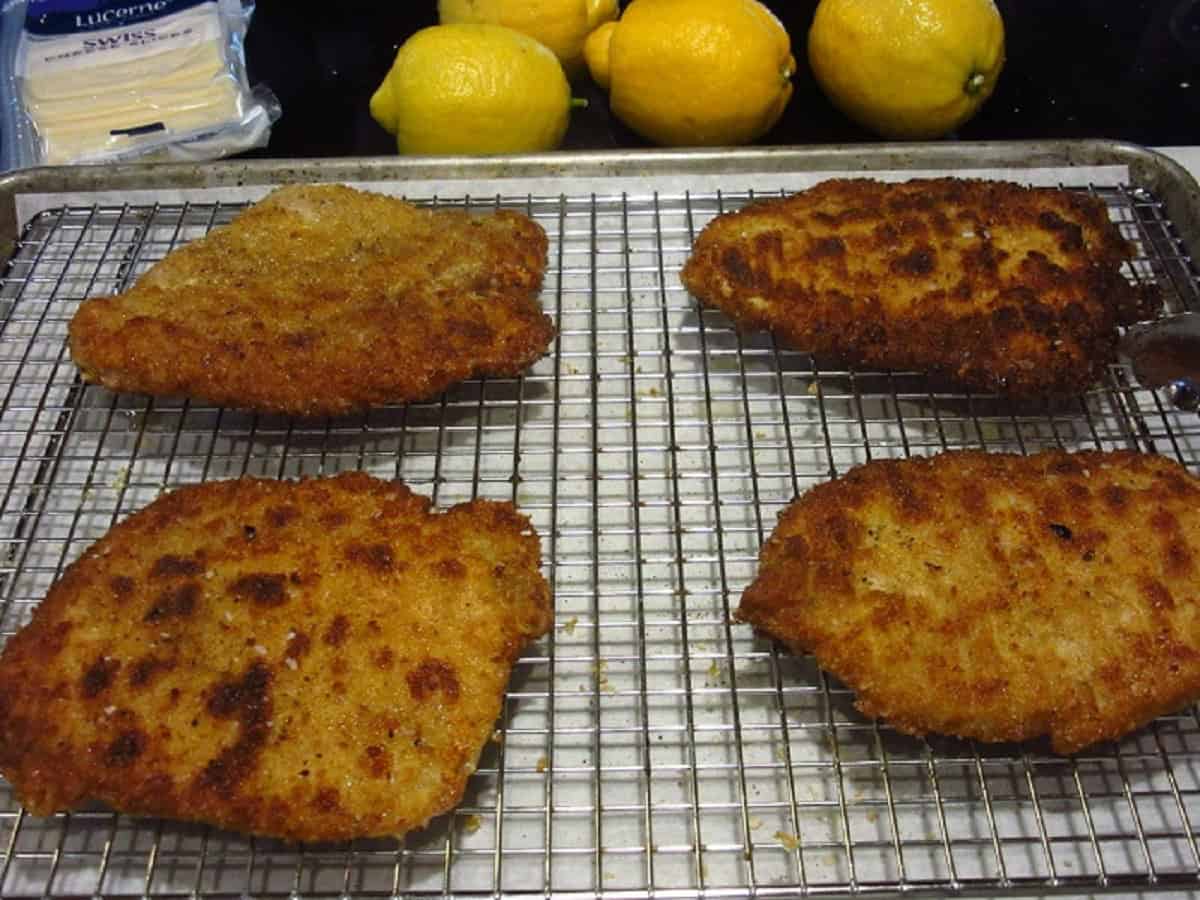 Four cooked and breaded pork cutlets on a cooking rack.