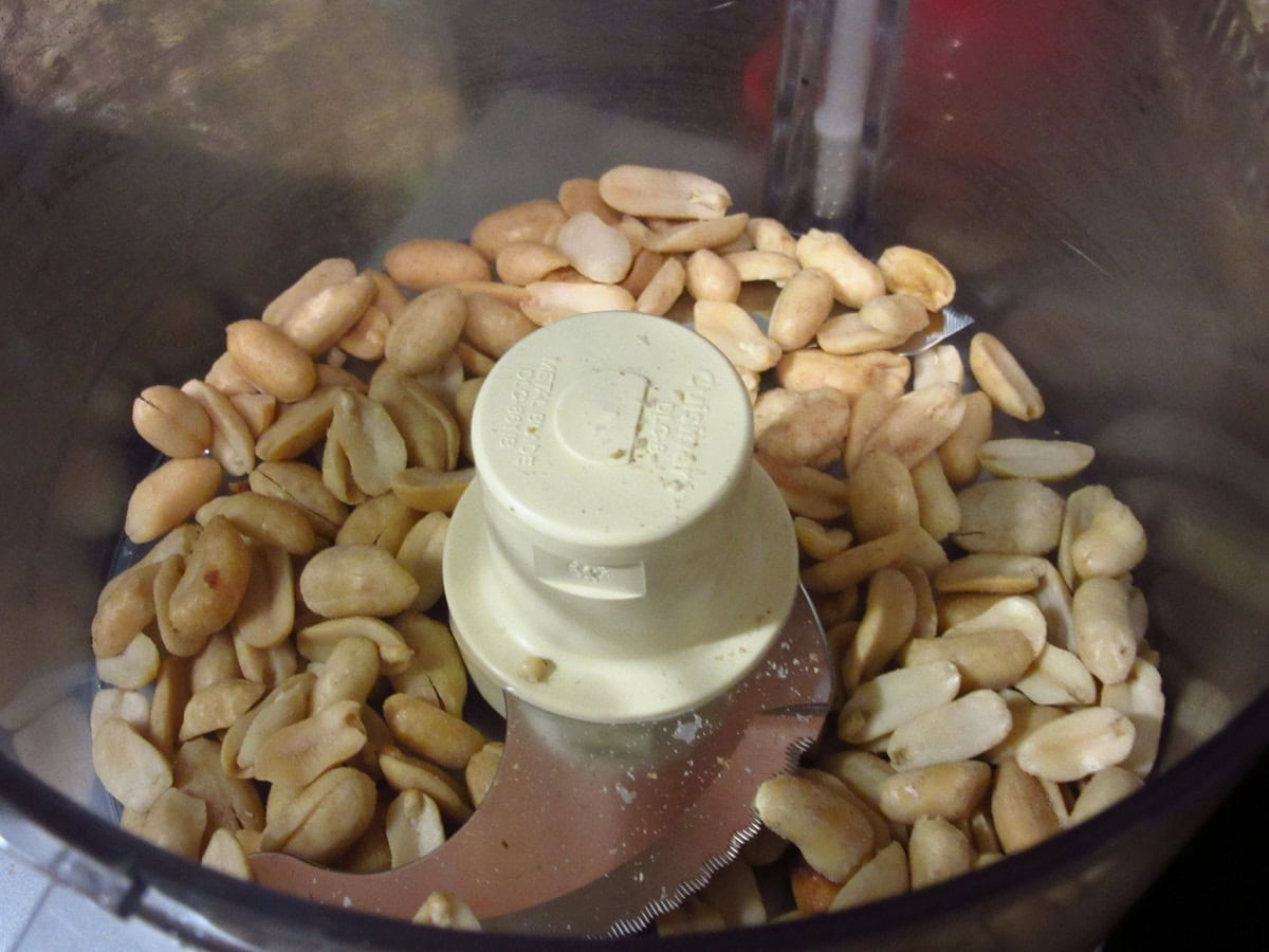 Peanuts in a bowl of a food processor before chopping.