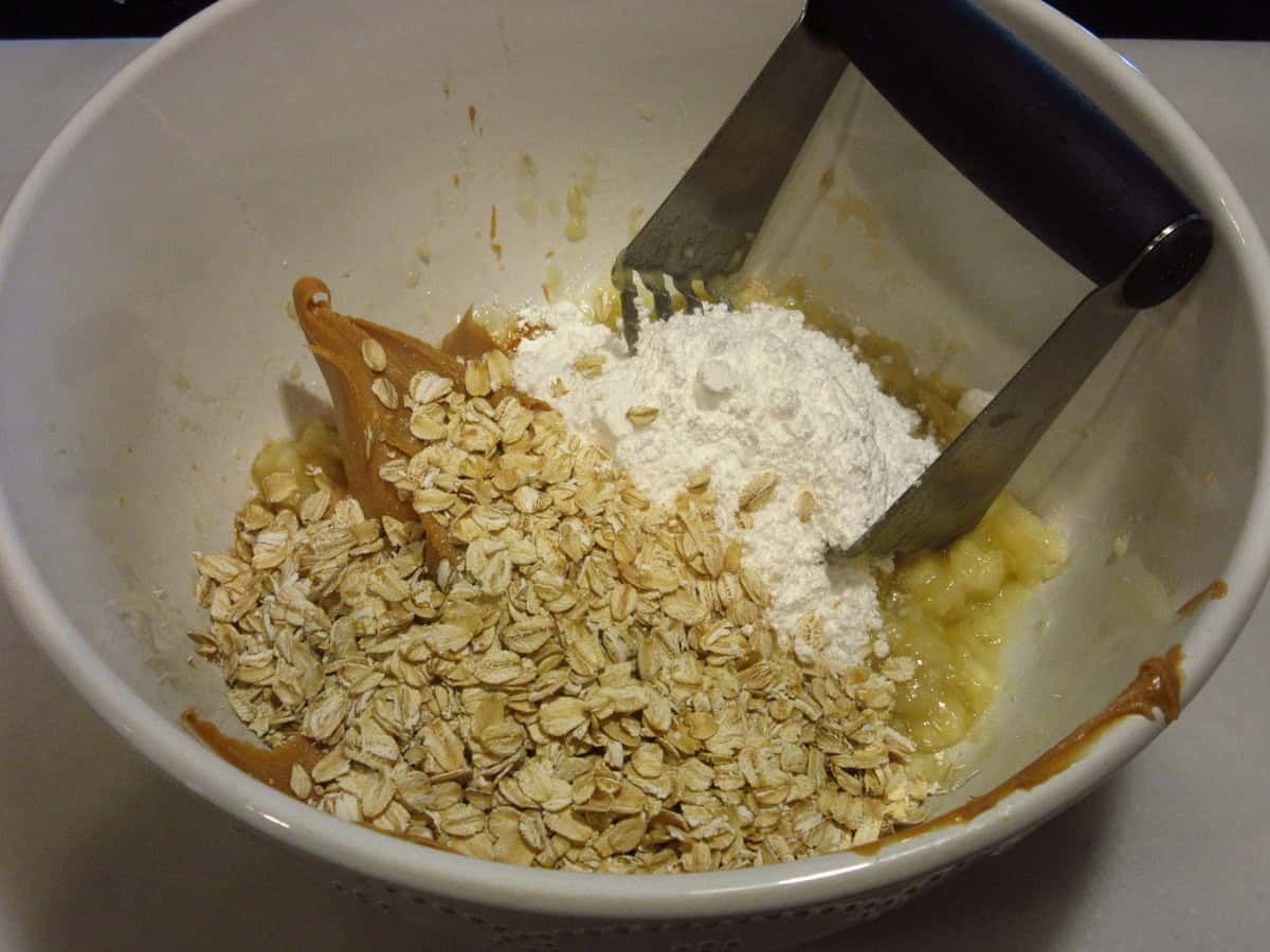 Oatmeal, peanut butter, bananas and flour in a white bowl.