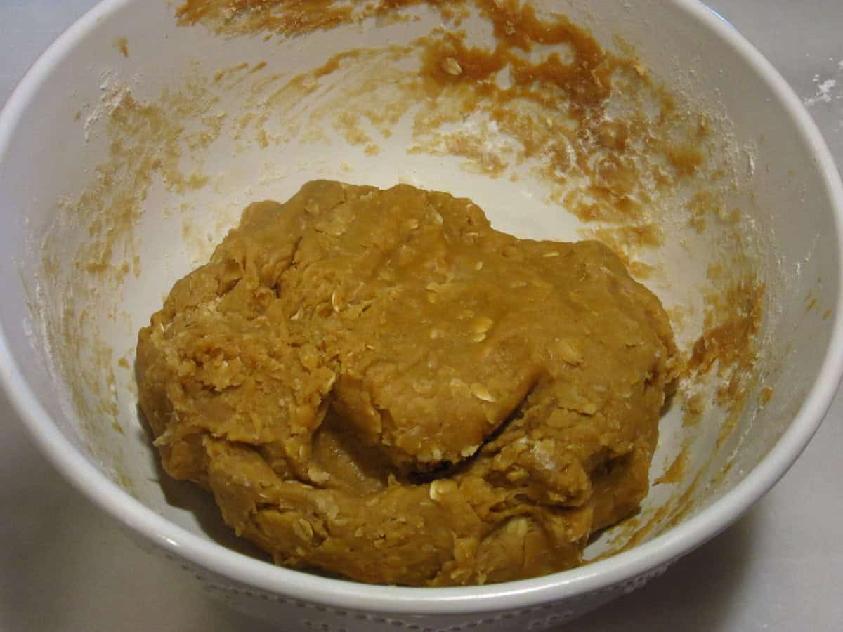 A raw oatmeal cookie dough in a white bowl.