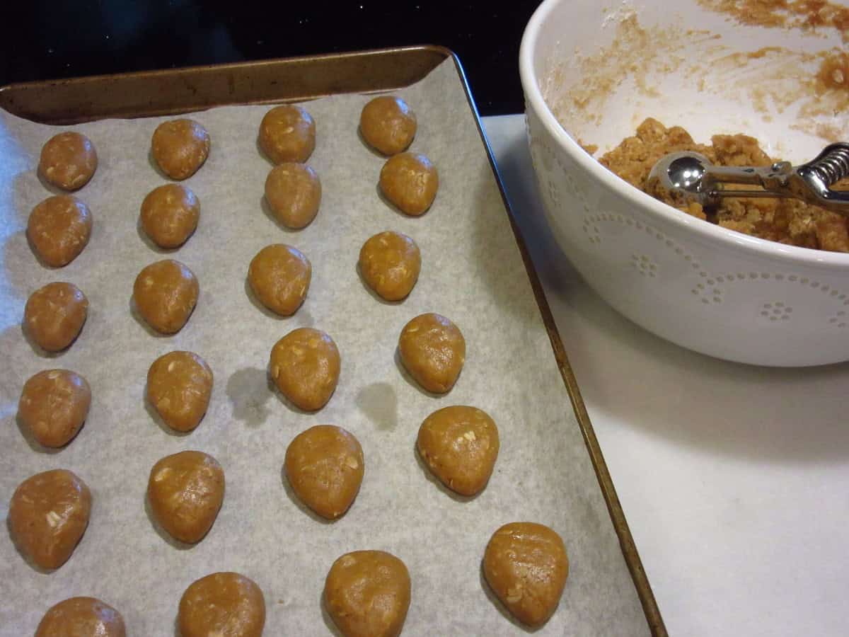 A baking sheet filled with unbaked acorn shaped cookies.