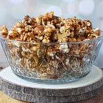 Two log slices with a glass bowl on top filled with homemade Caramel Corn with Bacon and Cashews.