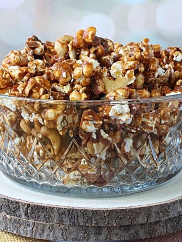 Two log slices with a glass bowl on top filled with homemade Caramel Corn with Bacon and Cashews.