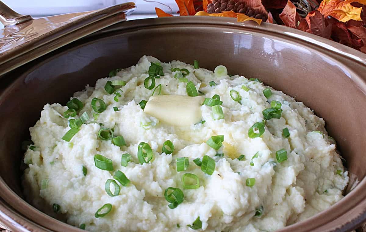 Mashed parsnips in a casserole dish topped with chopped scallions.