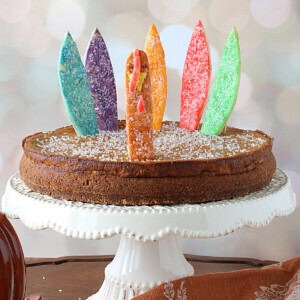 A fun and colorful pumpkin pie with colorful turkey feathers and head.