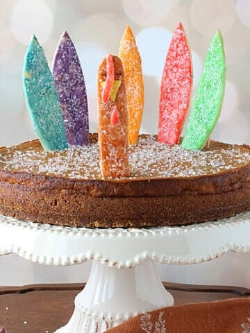 A fun and colorful pumpkin pie with colorful turkey feathers and head.
