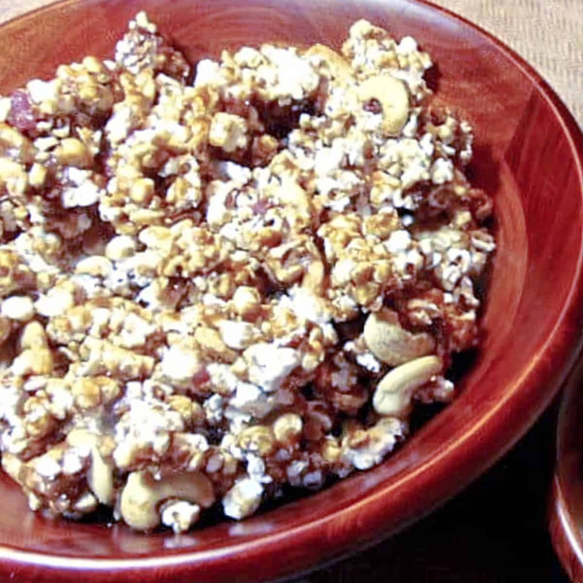 A brown bowl filled with Caramel Corn with Bacon and Cashews.