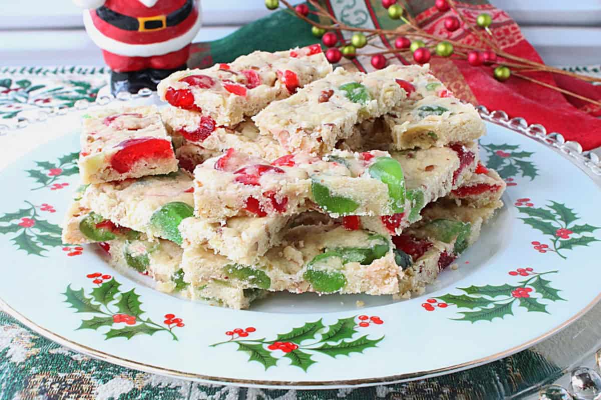 A holly berry plate loaded with a stack of red and green cherry slices for Christmas.