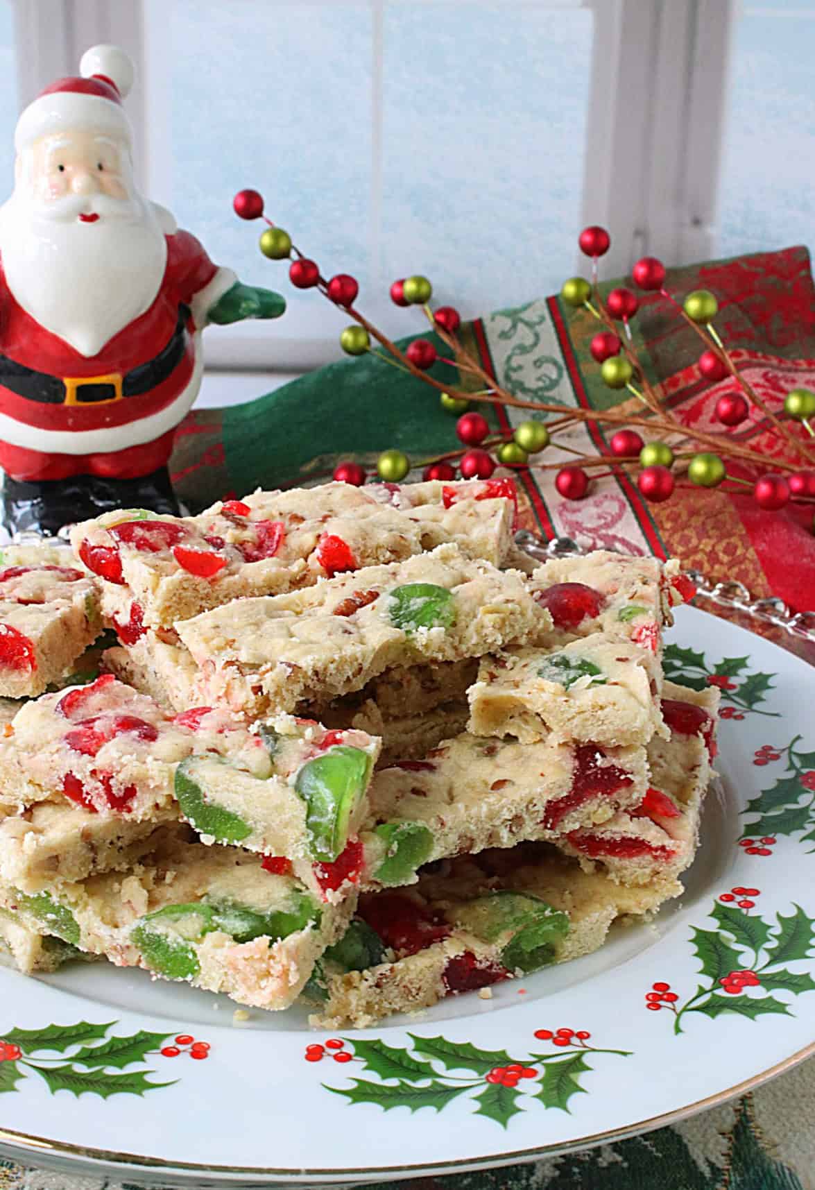 A ceramic santa by a window with a plate of festive red and cherry cherry slices.