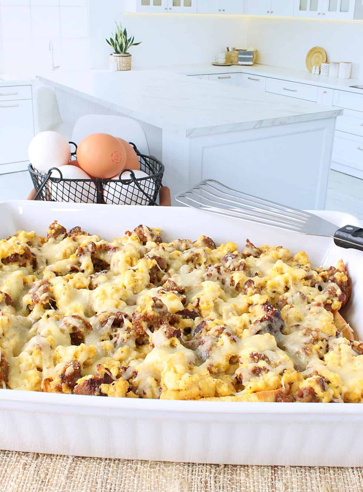 A kitchen scene with a scrambled egg and sausage casserole in the foreground.