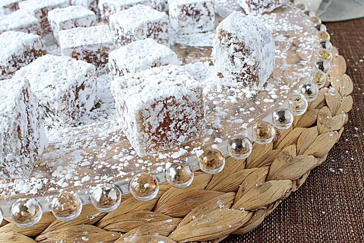 A glass platter with confectioner sugar dusted apple chews candy.