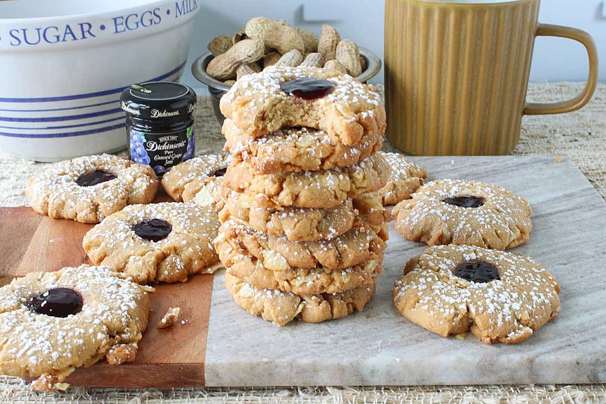 A stack of Peanut Butter and Jelly Potato Chip Cookies along with peanuts in the background.