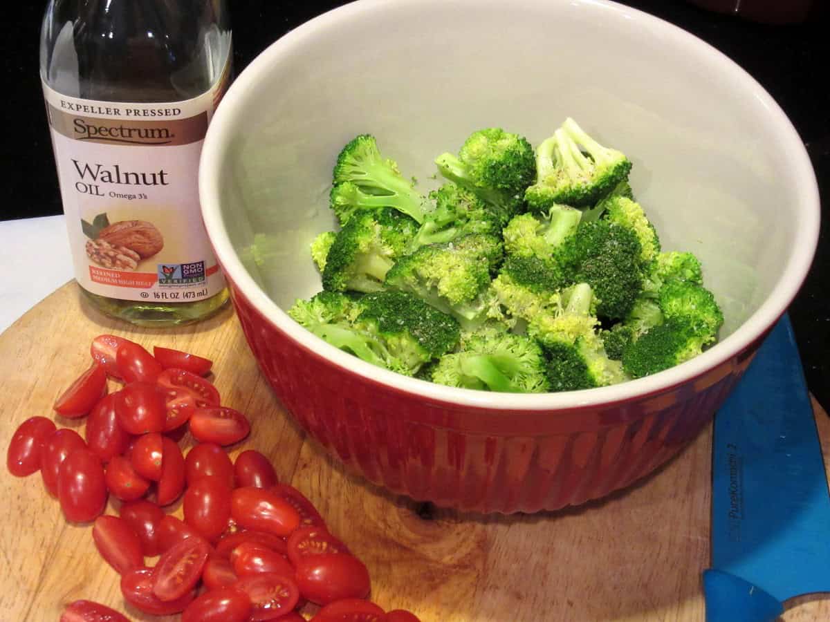 Broccoli florets in a bowl with tomatoes on the side.
