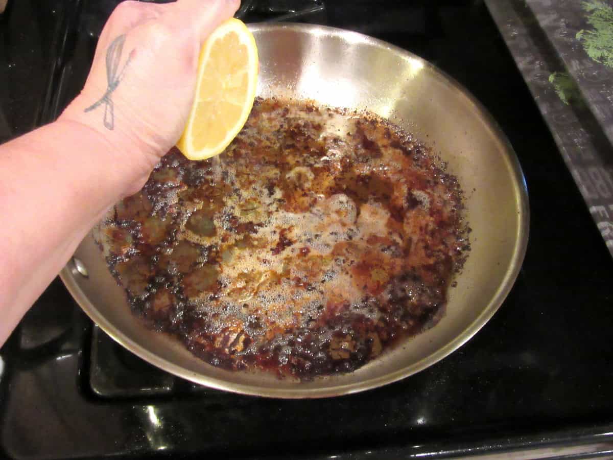 Lemon juice being squeezed into a skillet for deglazing.