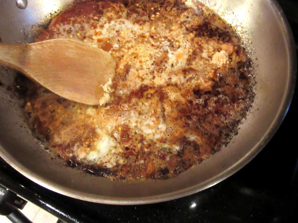 Deglazing a skillet with a wooden spoon.