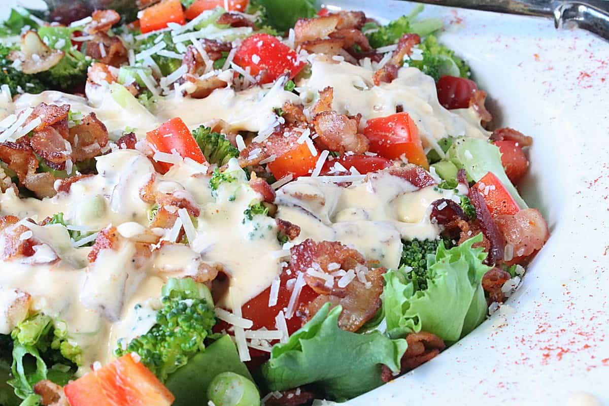 A colorful red and green Christmas salad topped with dressing and cheese.