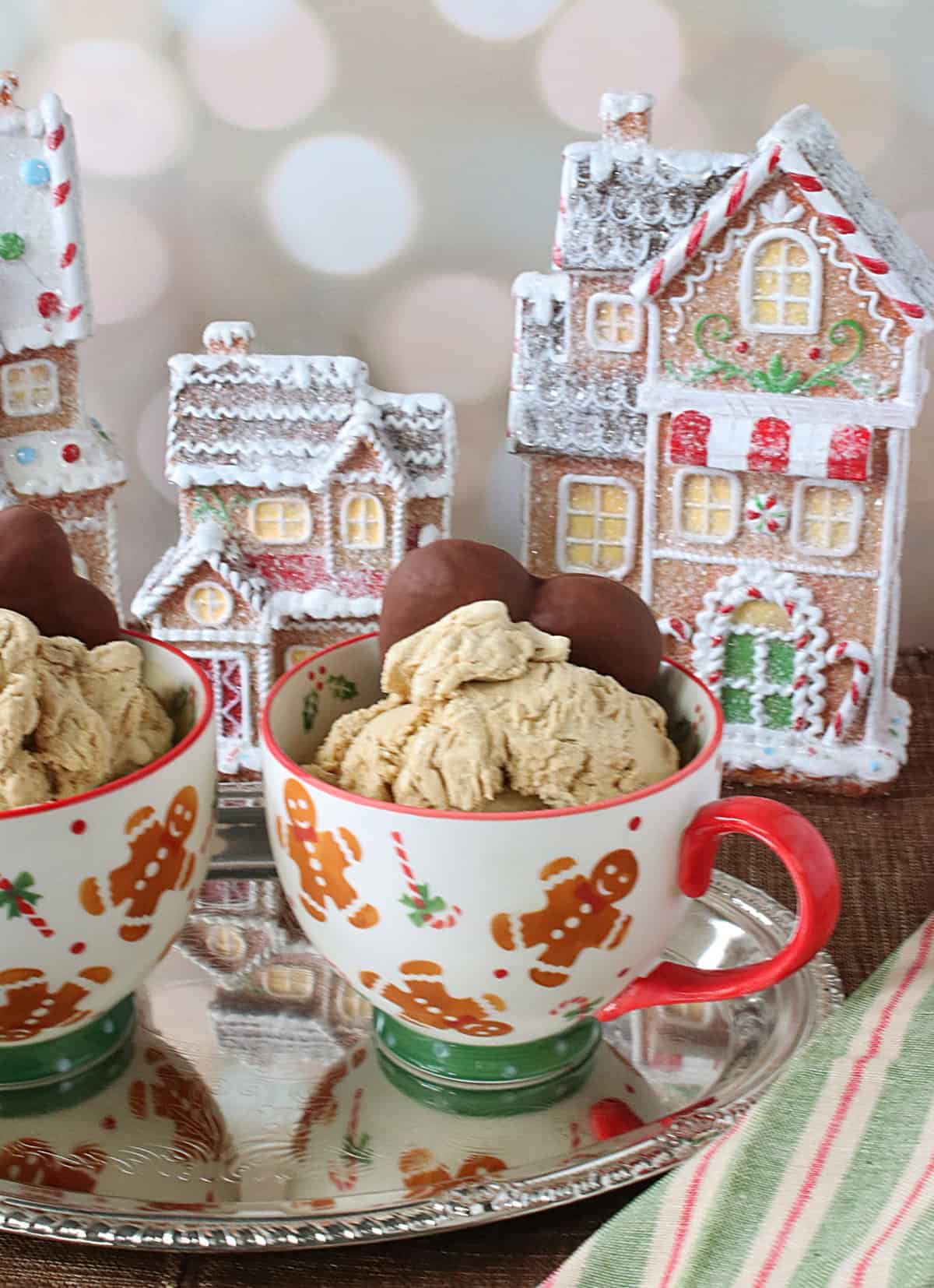 Cute, sparkly gingerbread houses in the background and gingerbread cups filled with ice cream in the foreground.
