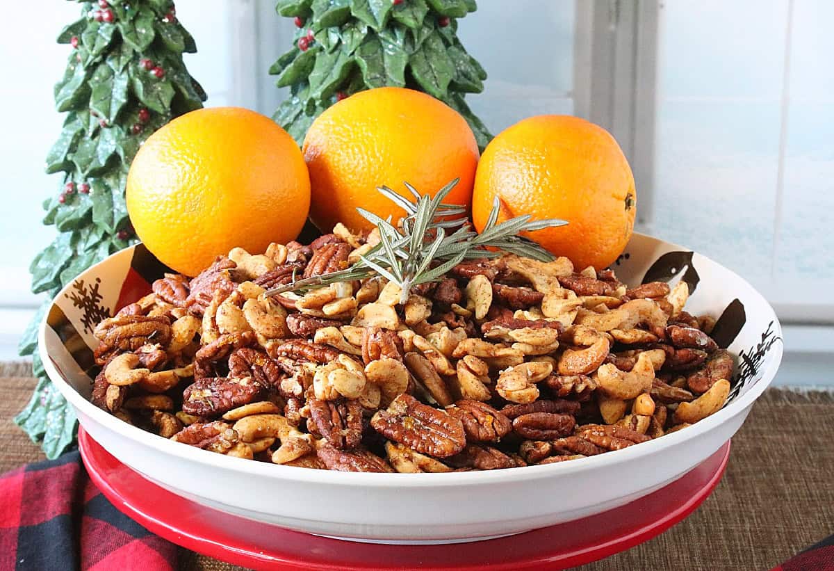 A bowl of orange and herb spiced nuts by a winter window.