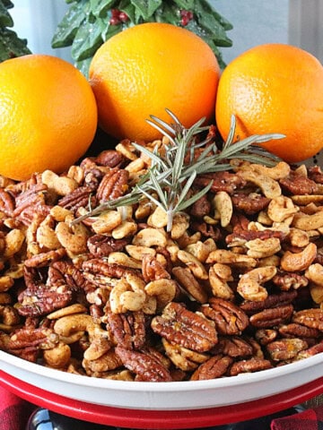 Cashews and Pecans in a bowl with rosemary and oranges.