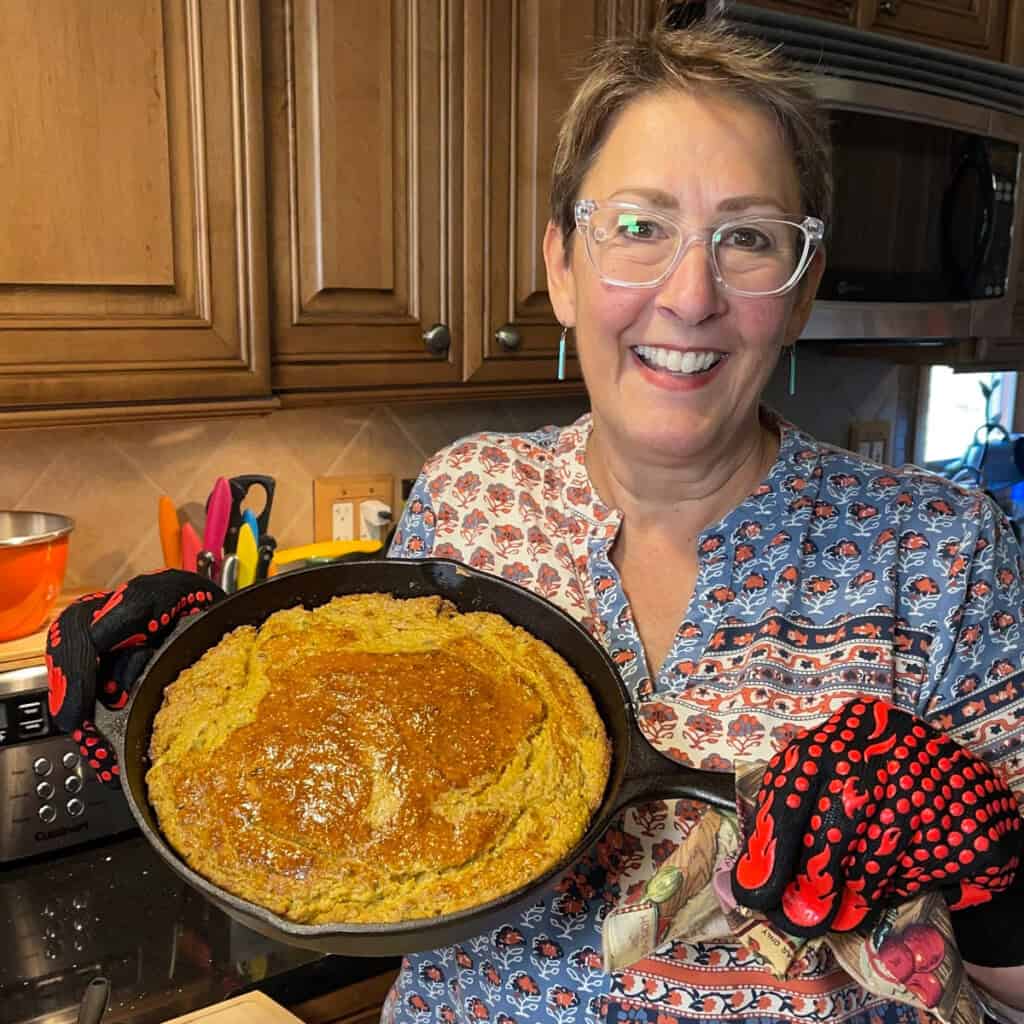 Renee of Kudos Kitchen by Renee holding a cast iron skillet cornbread.