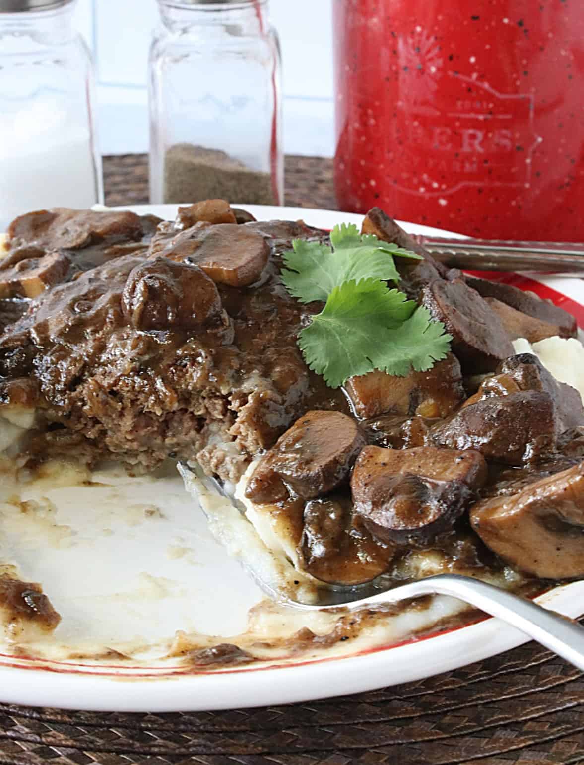 A partially eaten Salisbury Steak on a plate with a fork.