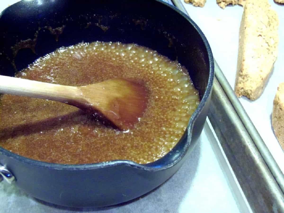 Amaretto caramel sauce in a saucepan with a wooden spoon.
