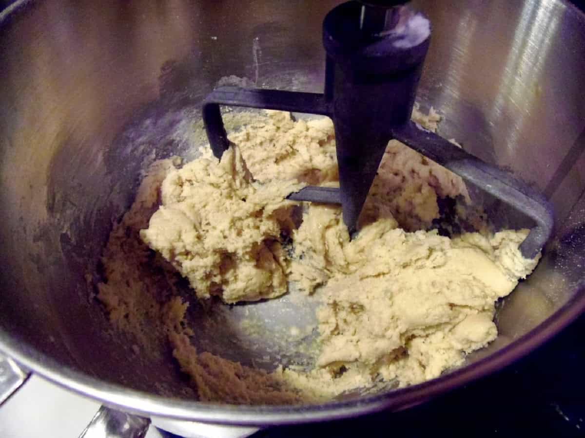 A paddle attachment in a stand mixer with cookie dough.