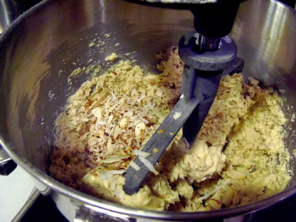 A stand mixer with a paddle attachment in a bowl of biscotti dough.