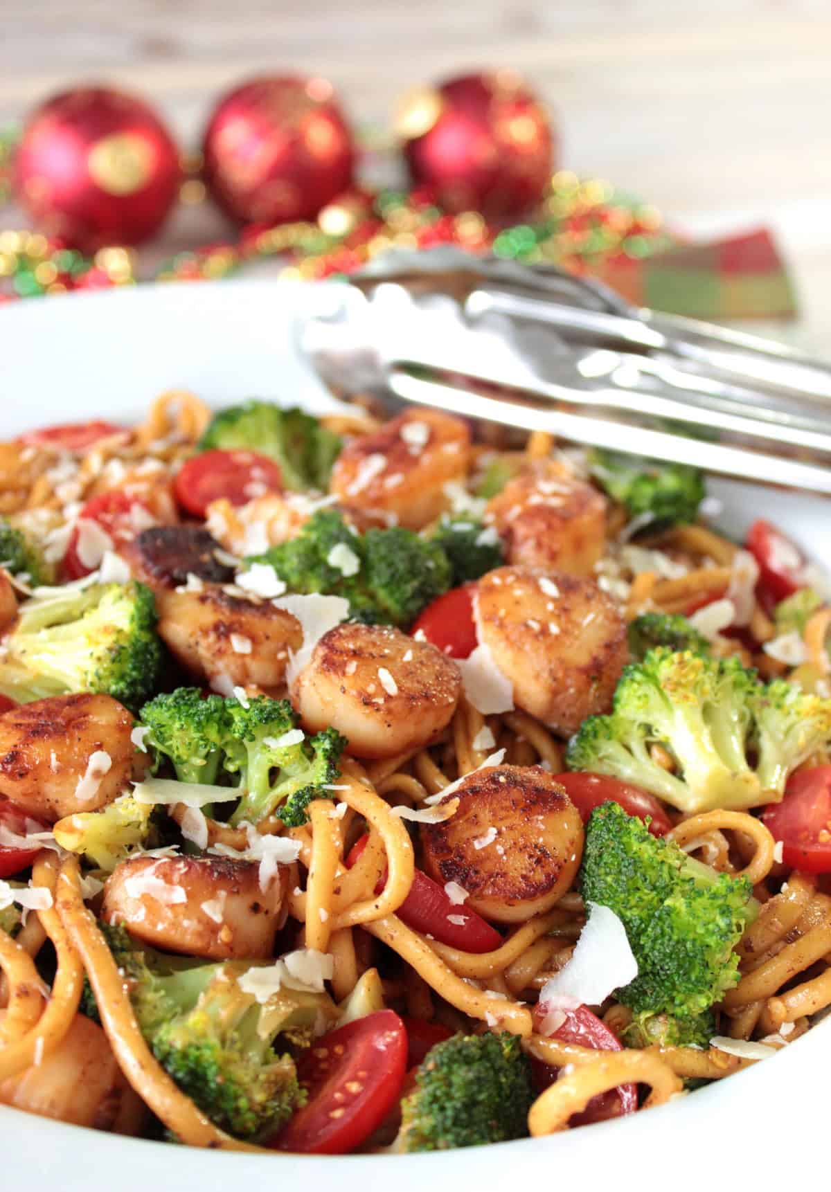 A colorful bowl of caramelized scallops with broccoli tomatoes and linguine.