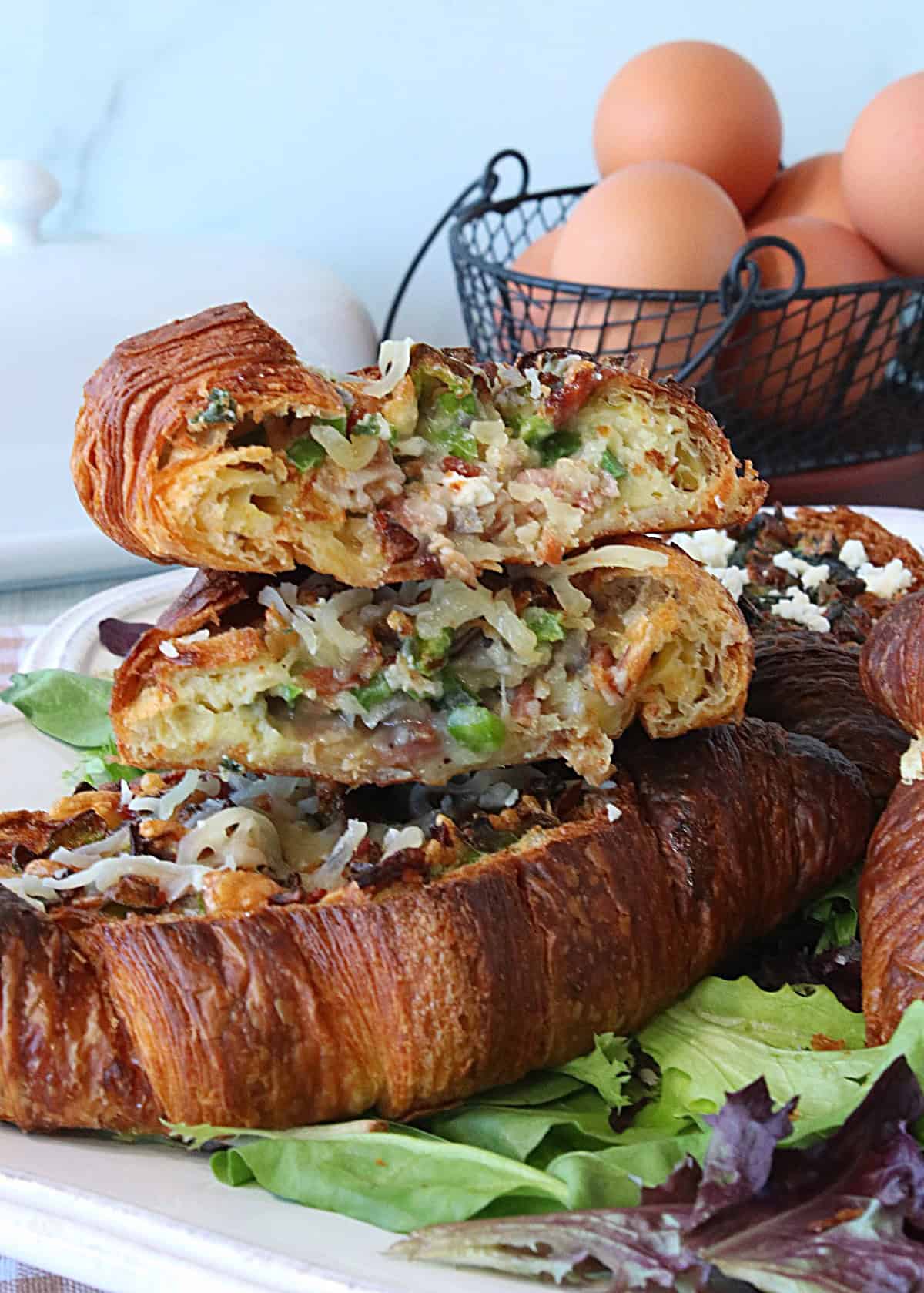 The yummy insides of a egg and vegetable stuffed croissant breakfast sandwich.