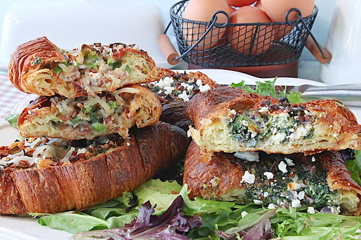 Two breakfast egg and croissant sandwiches stacked on top of each other.