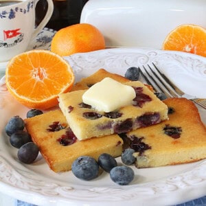 An inviting plate of sheet pan pancakes with blueberries and oranges on a white plate.