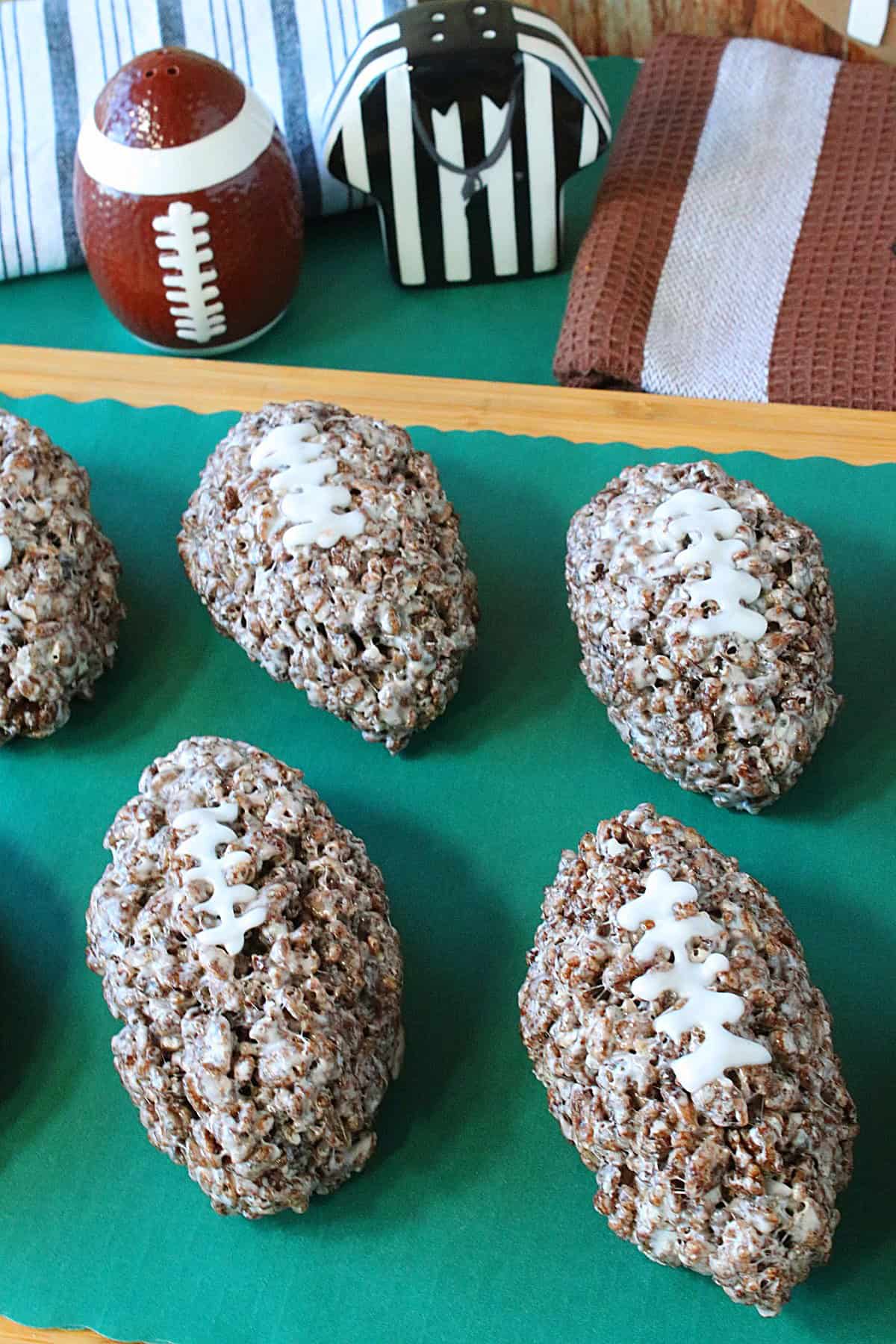 Some cocoa krispies football treats on a green tray with football accessories in the background.