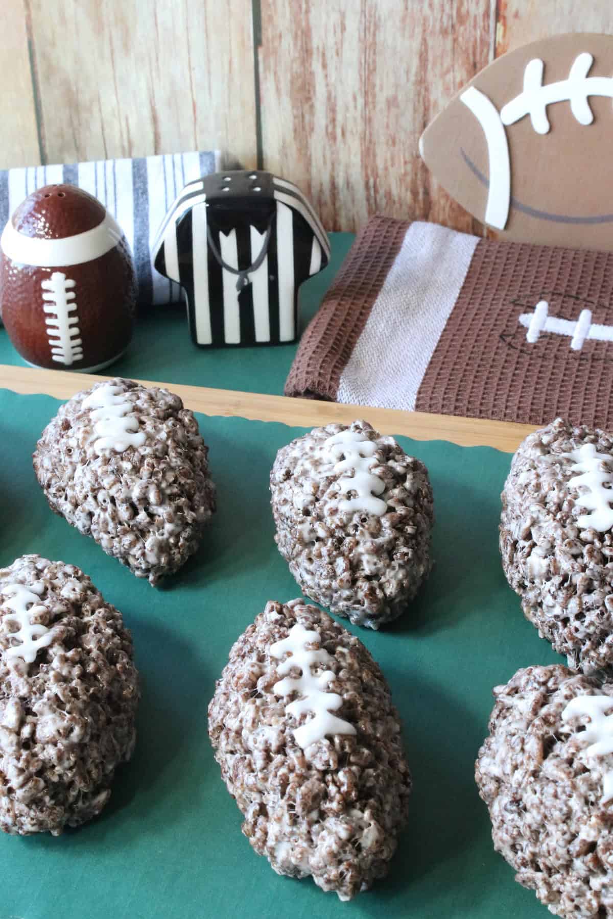 Cocoa Krispie Treat footballs on a green plate with football stuff in the background.