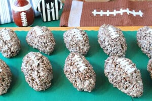 A bunch of cocoa krispies marshmallow football treats lined up on a green placemat.