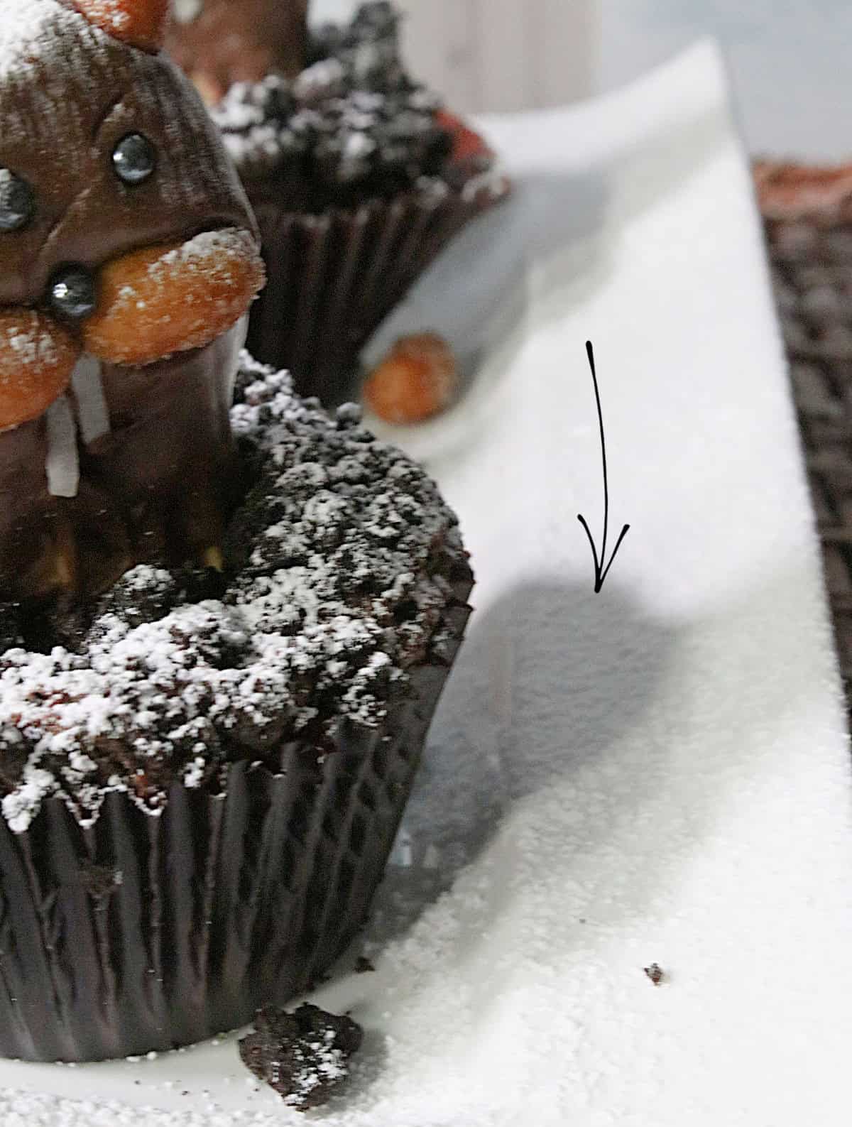 The shadow given off from a groundhog cupcake on a white plate.