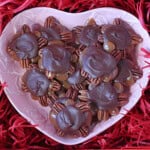 A pink heart dish filled with homemade pecan turtles.