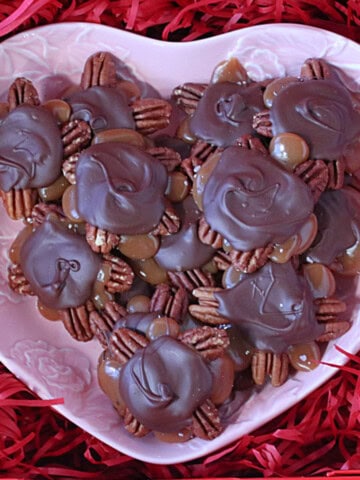 A pink heart dish filled with homemade pecan turtles.