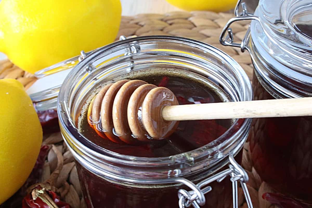 A honey dipping stick in a jar of hot honey.