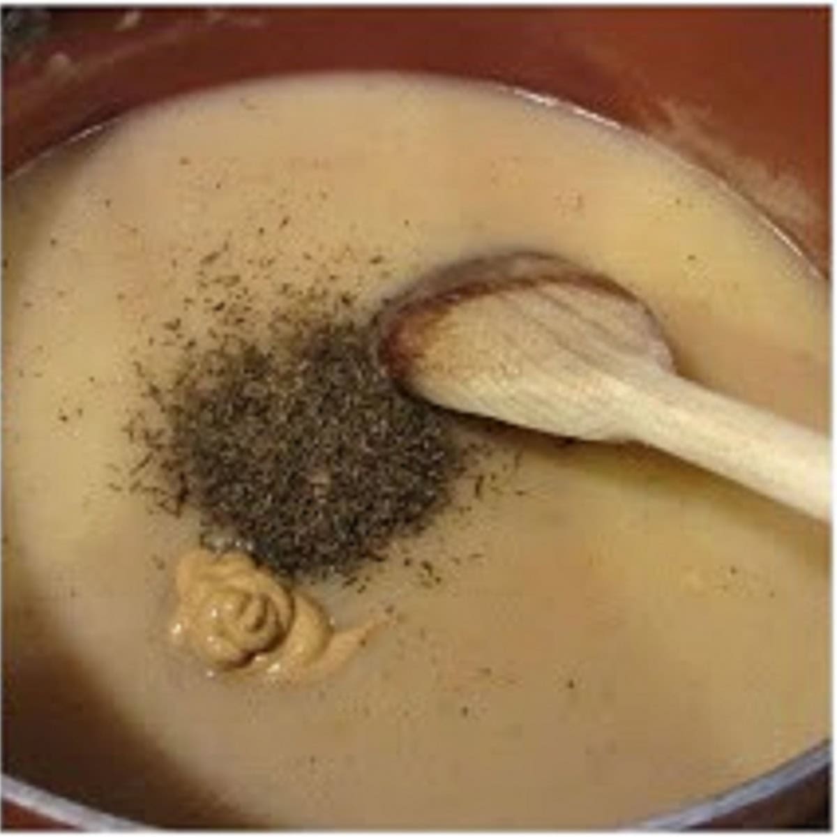 A creamy chicken sauce with herbs and mustard in a pan.