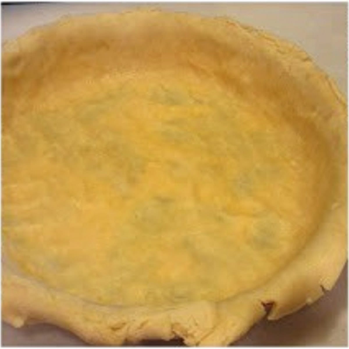 A pie crust in the bottom of a pie pan.