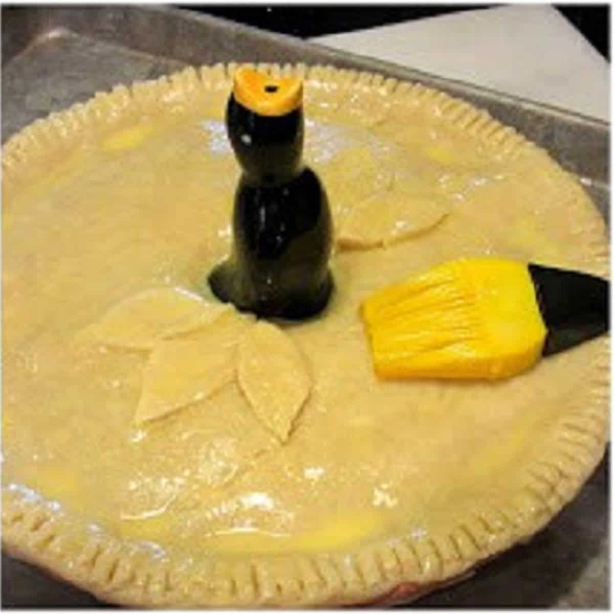 Egg wash brushed onto a pork pot pie with a pie bird.
