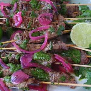 Luscious beef skewers with chimichurri sauce, limes, and rec onion.