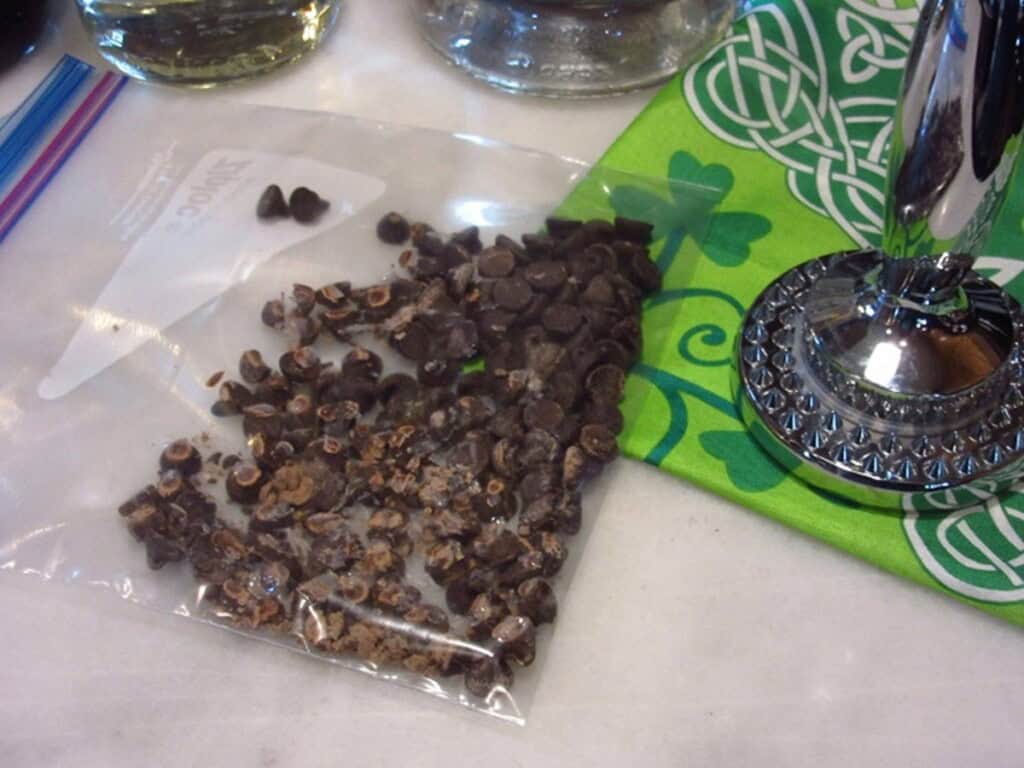 Chocolate chips in a plastic bag with a meat mallet next to it.