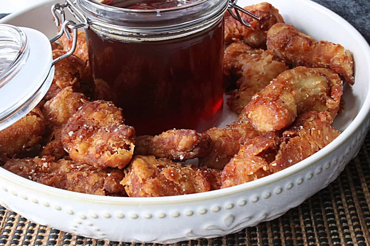 Crispy and brown fried chicken nuggets in a bowl with honey dipping sauce.